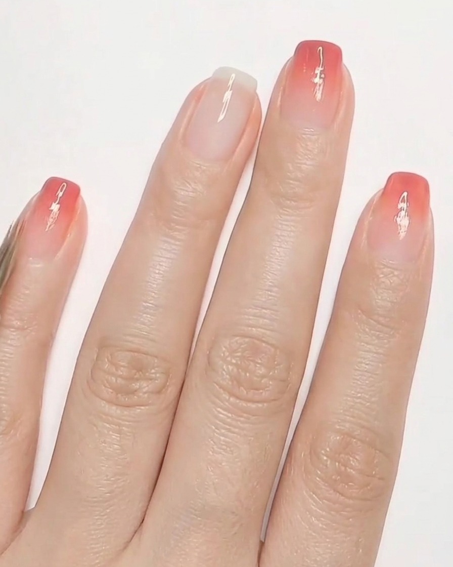 A tiny detailing brush painting small red heart shapes onto a fingernail with a milky white base.