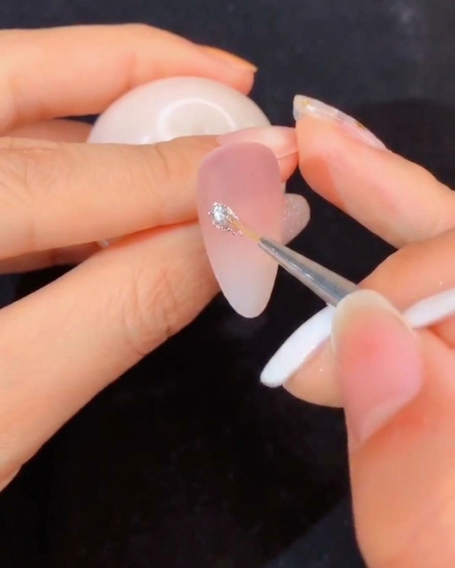 A close-up of a liner brush dipping into an open jar of clear modeling gel.