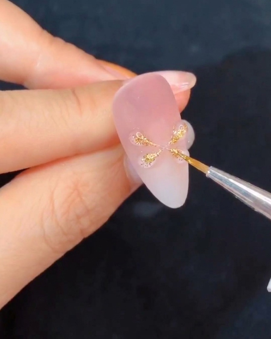 A hand holding a nail under a curing lamp, highlighting the newly formed gel details.