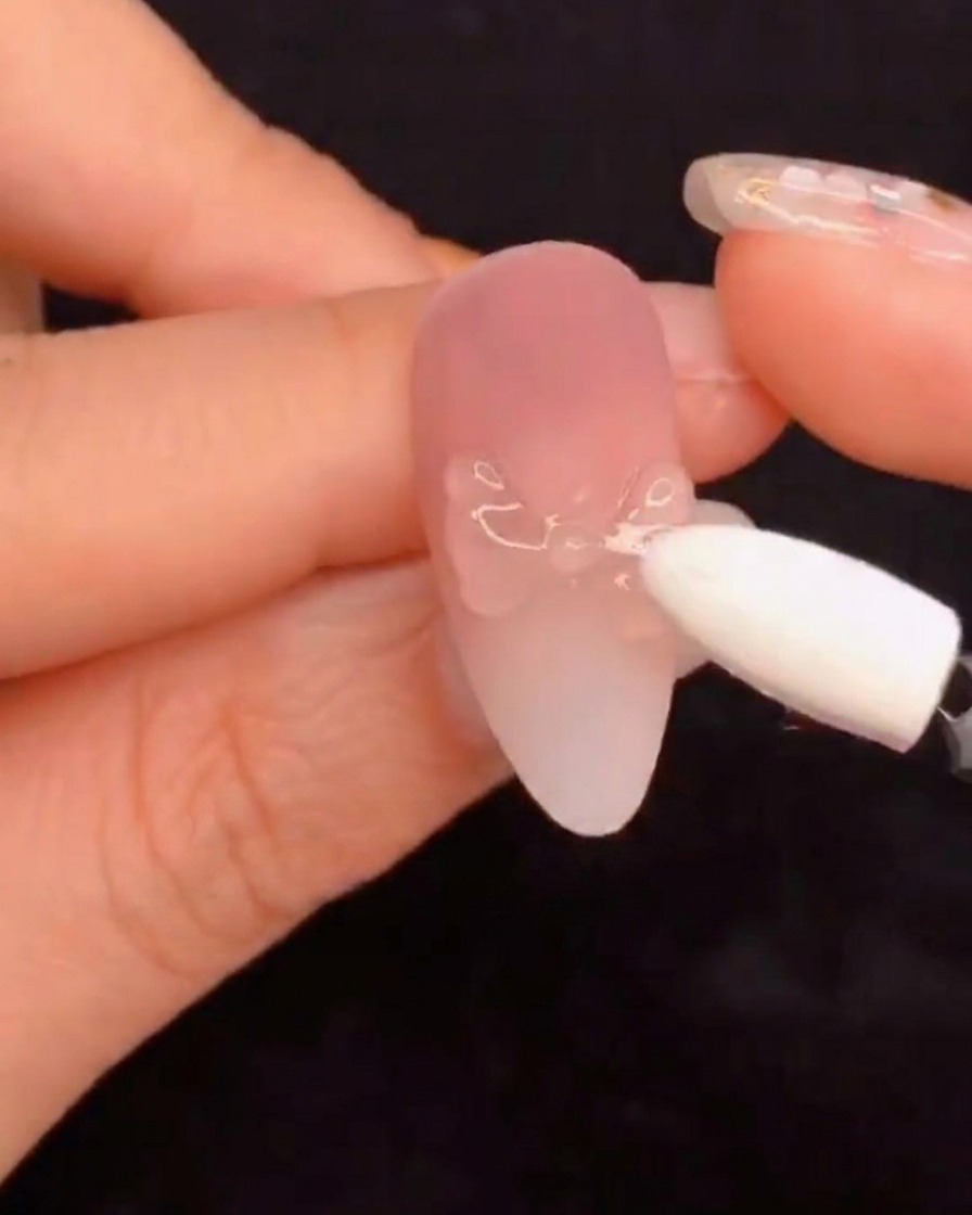 A silicone sponge applicator rubbing aurora pigment powder onto a sculpted nail design.