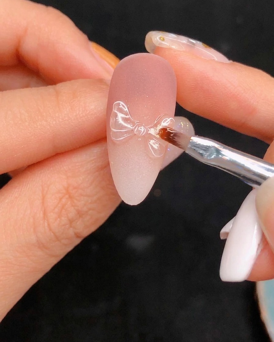 Applying the final glossy top coat over the detailed nail art.