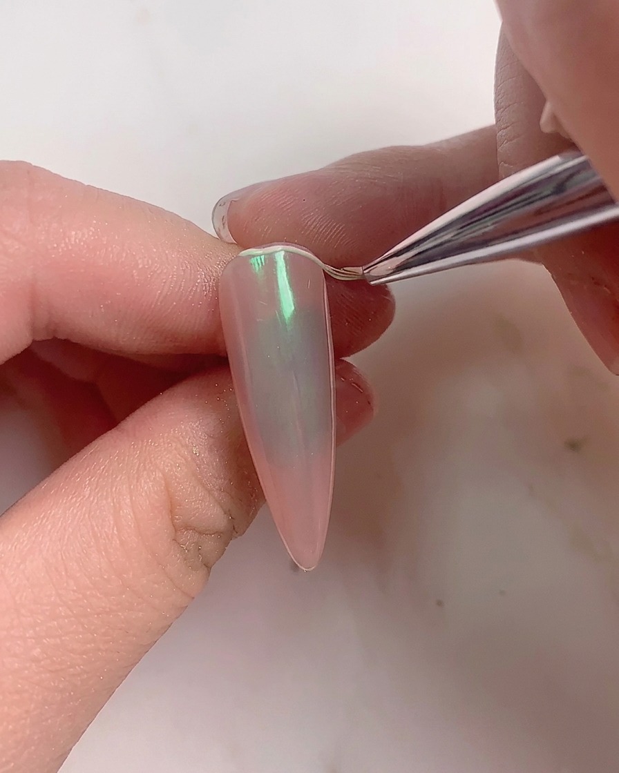 A soft brush sweeping excess powder off a finished aurora nail.