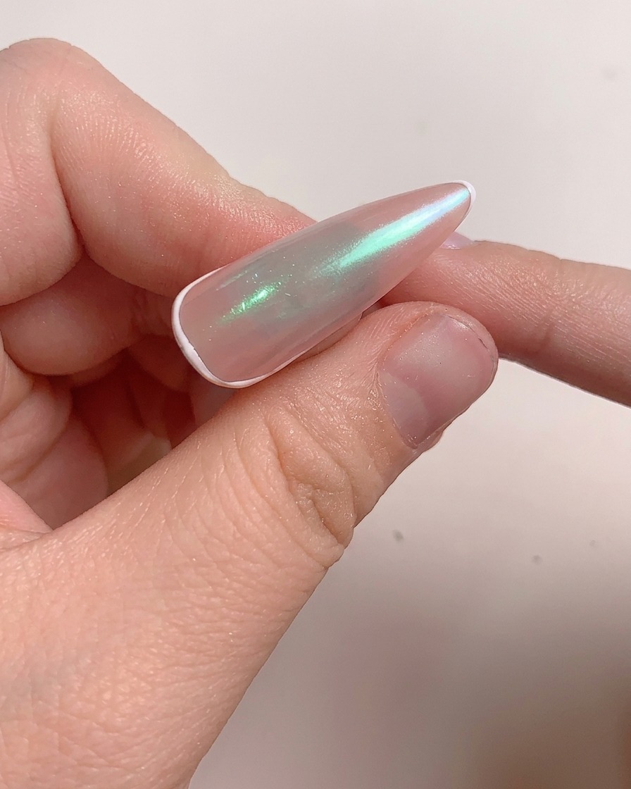 A brush applying a layer of reinforcing gel onto the polished nail.