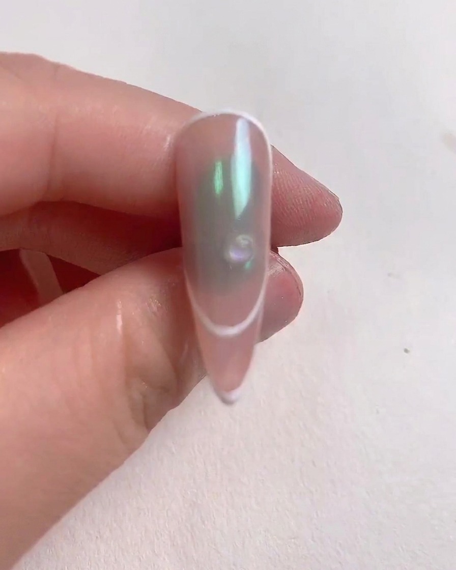 A small clear drop of reinforcing gel placed on the center of a decorated nail.
