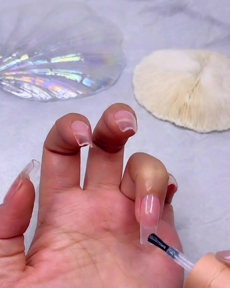 Adding a second layer of milky white gel to the nail tip to build the gradient intensity.