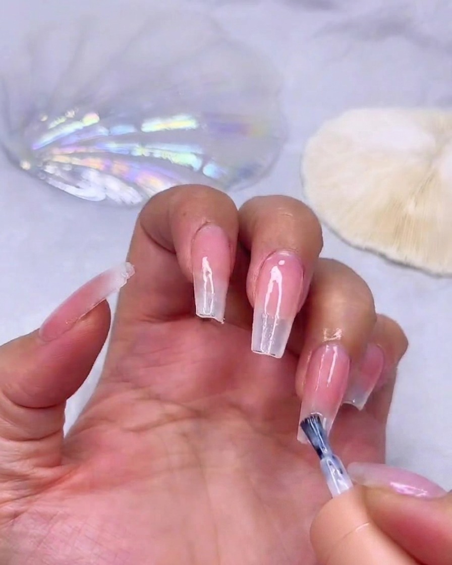 Applying a third layer of milky white gel to the very tip of the nail for maximum opacity.