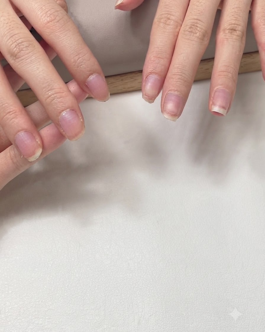 A set of natural short fingernails with clear extension forms neatly attached in preparation for nail lengthening.