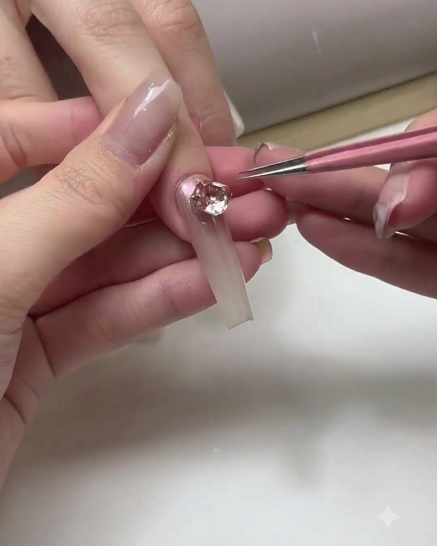A manicurist applying a clear top coat layer across the surface of completed ombre nails.