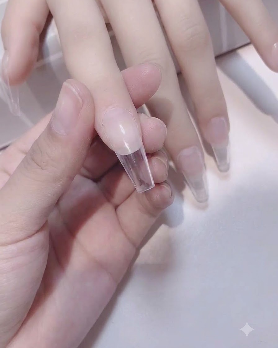 A sponge brush applying a second layer of white gel to the nail tip.