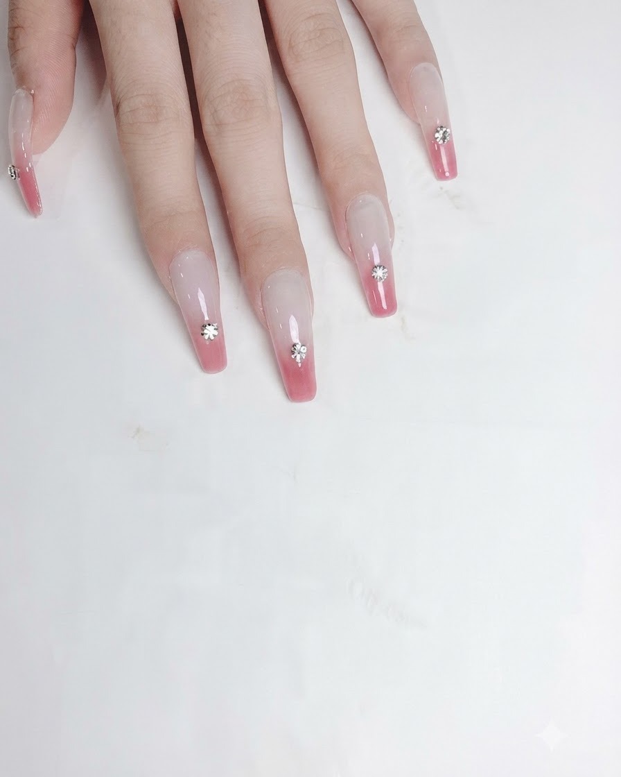 A detailing tool applying a dab of thick clear adhesive gel into the carved pocket on a nail.