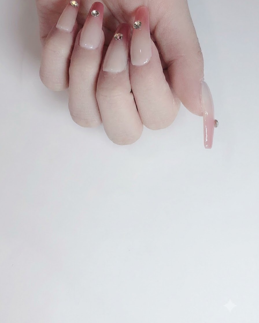 A pair of tweezers carefully placing a sparkling crystal rhinestone onto the adhesive spot on a nail.