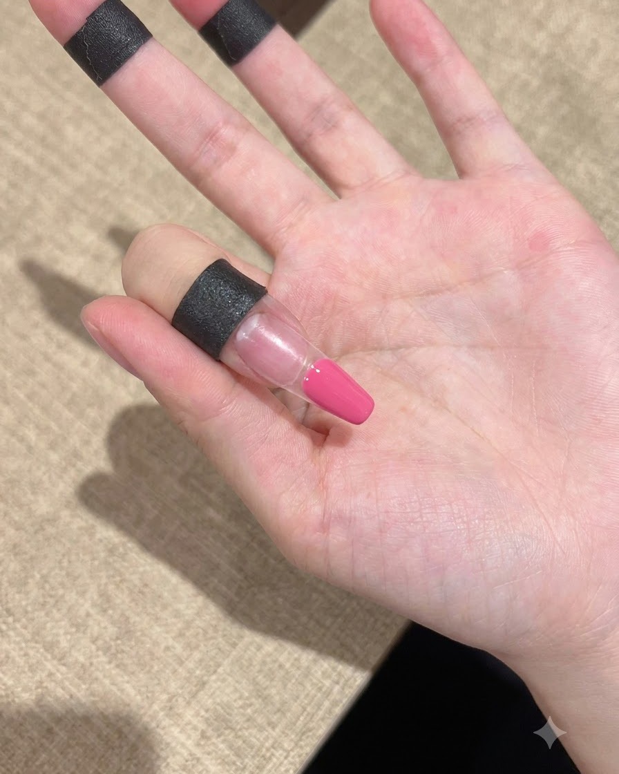A close-up of a finger with pink gel applied neatly on the tip area.