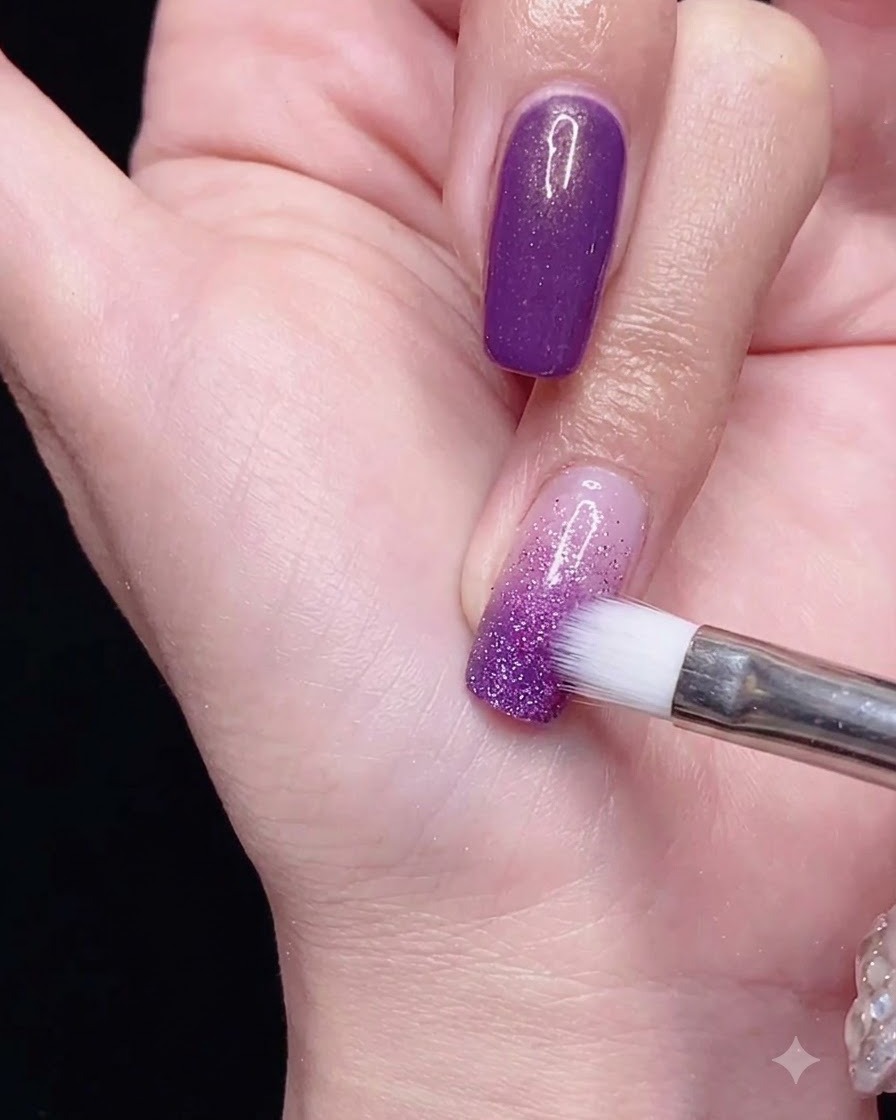 A gradient brush blending purple gel polish downward over the nail for a smooth ombre effect.
