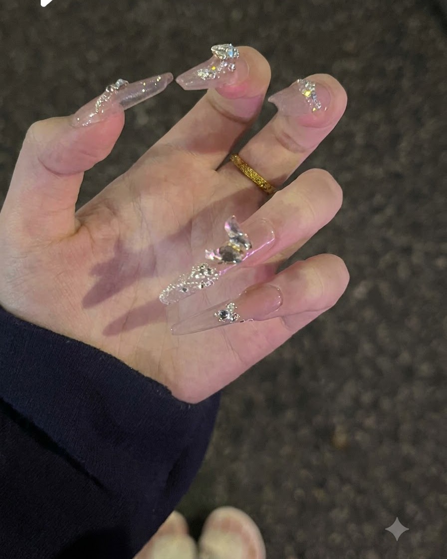 A hand turned upwards to display top-surface glitter and sparkling diamond crystals on nude nails.