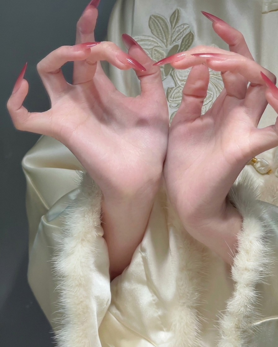 Close-up of curled fingers showing long stiletto nails with a smooth transition from a sheer base to red tips.