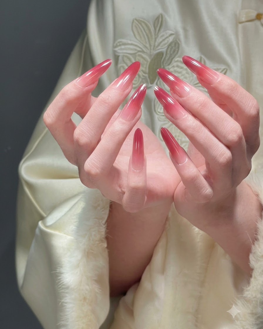 Two hands cupped together presenting all fingers to display a complete festive red ombre manicure.