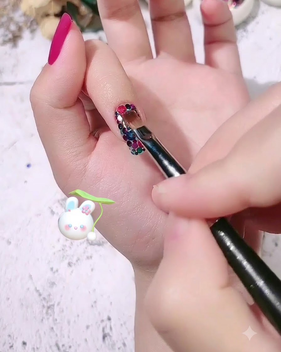 A nail brush applying a clear layer of modeling gel over the patterned sequin nail design.