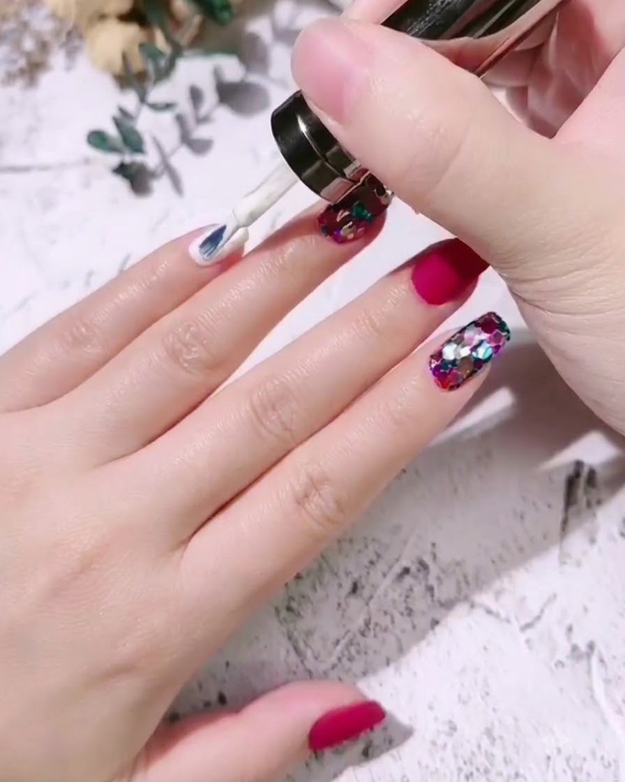 A nail brush applying milky white gel polish onto the nail of a pinky finger.