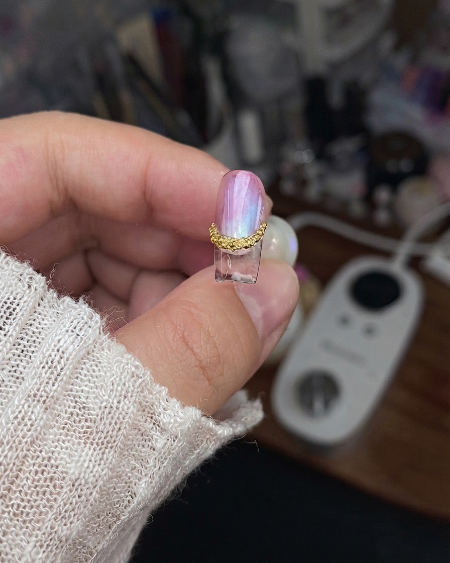 A finished nail piece held up to show the sealed edges and completed design details.
