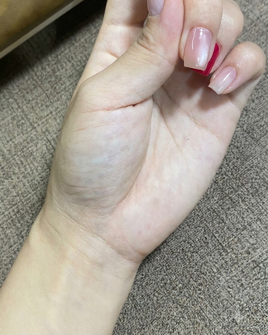 A close-up shot of a hand resting while a portable UV LED lamp cures the gel polish on the nails.