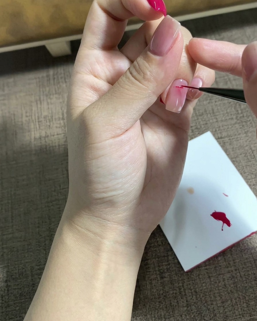 A fine liner brush drawing a detailed magenta star motif onto a prepped nail surface.