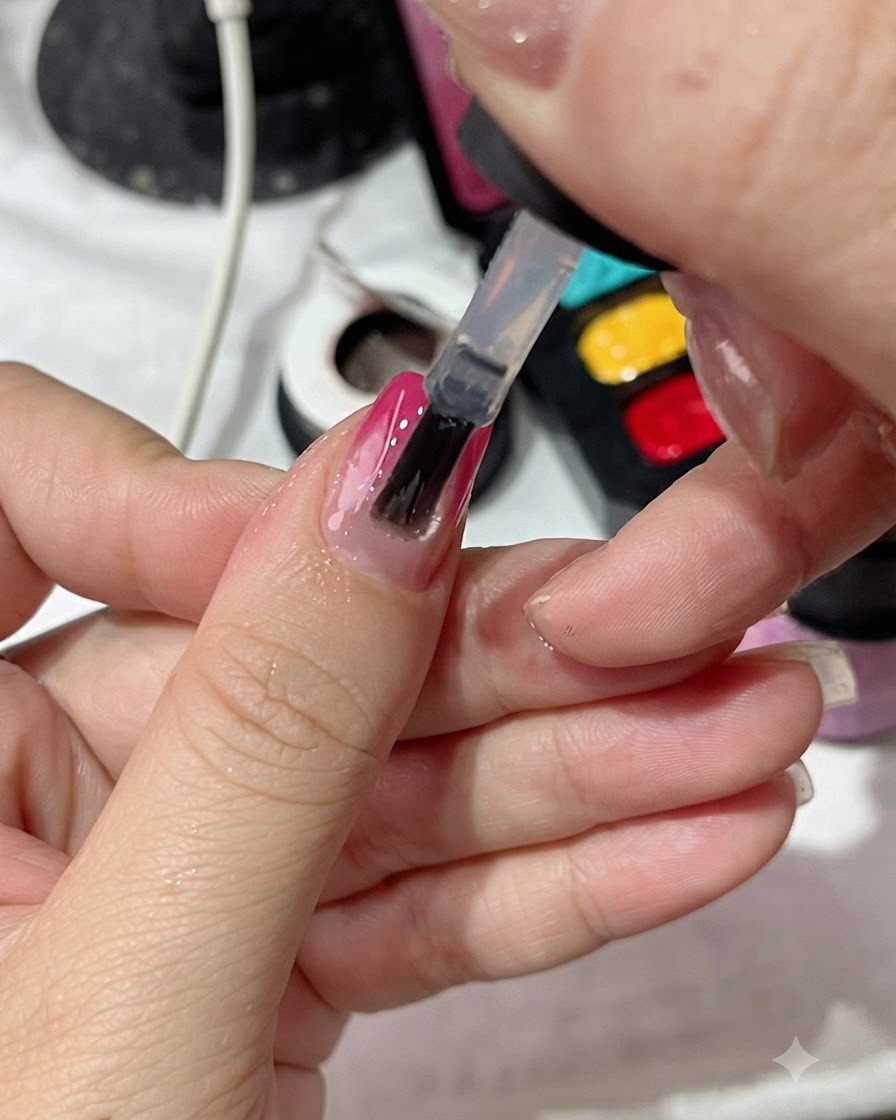 A polish brush applying a clear top coat evenly over a gradient manicured nail.