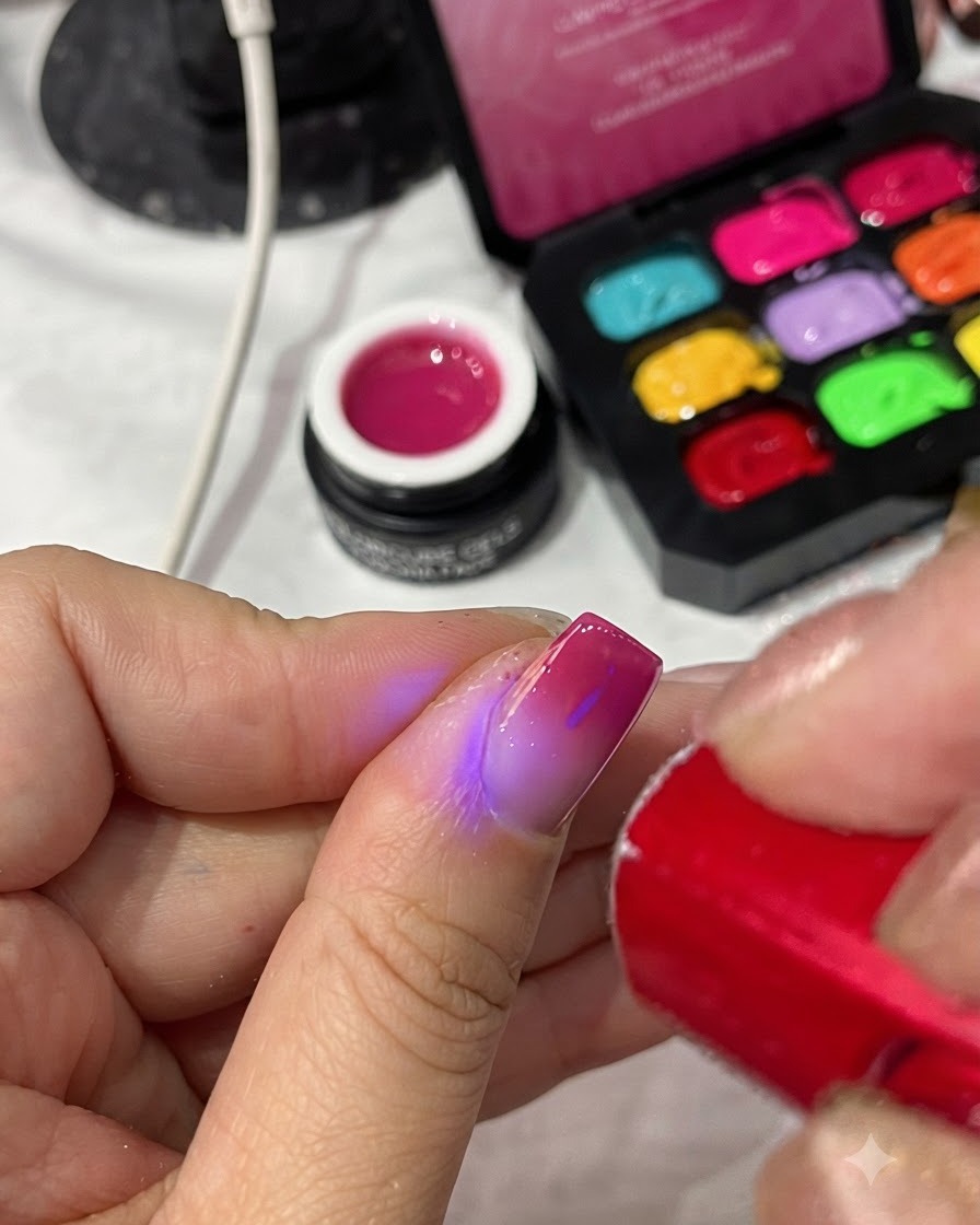 A portable red UV/LED lamp curing the top coat on a completed manicure.