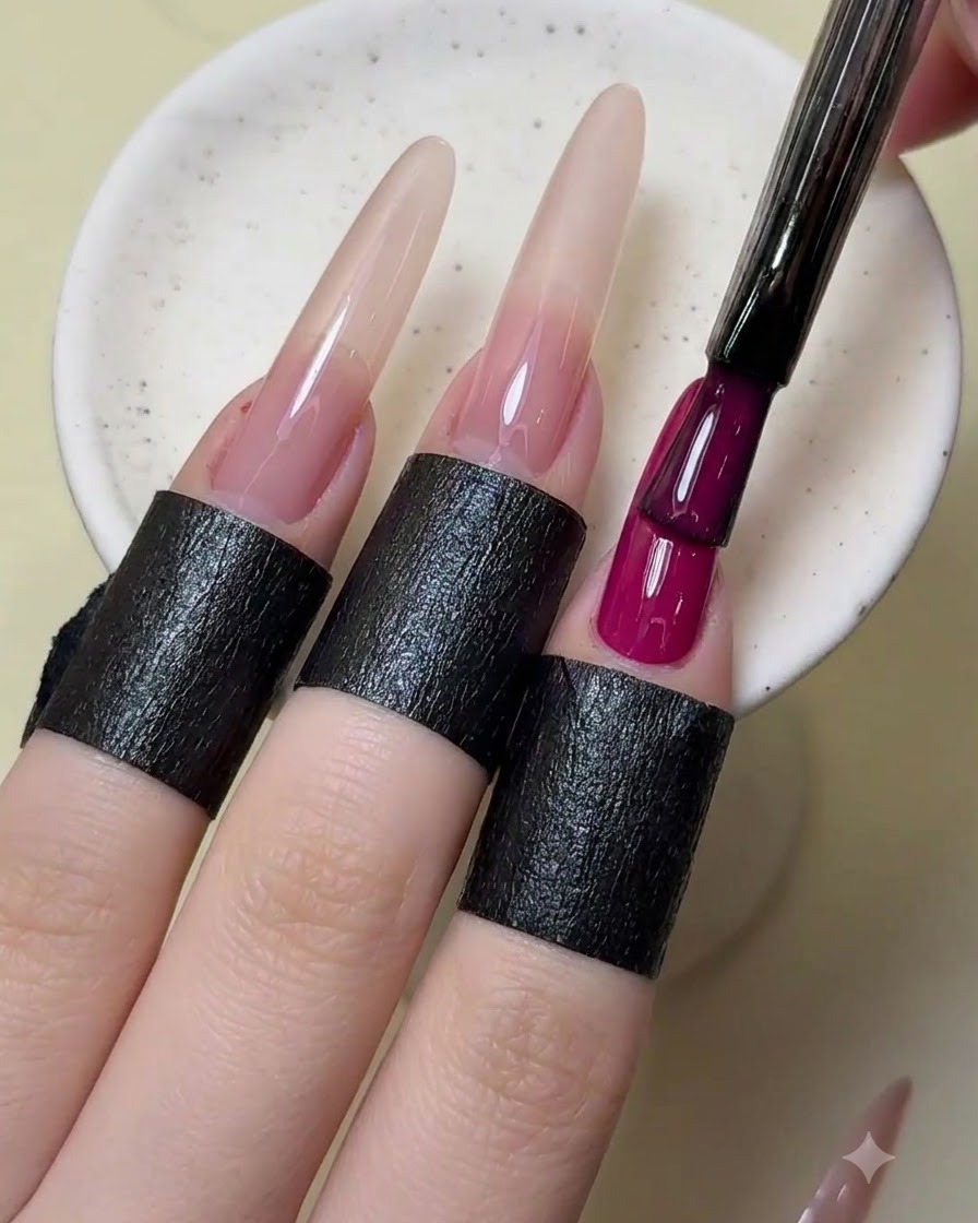 A nail brush adding a second layer of opaque magenta red polish to the index finger.