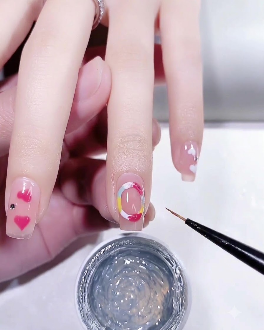 A fine brush applying clear 3D modeling gel over the colorful painted circles on a nail.