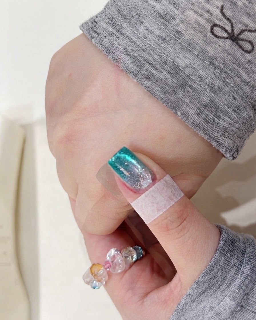 A hand placed inside a UV nail lamp to cure the freshly applied watercolor pigment layer.