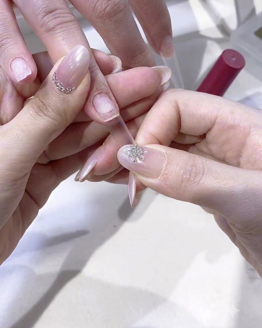 A finger with an attached nail extension being cured under a small handheld UV/LED lamp.