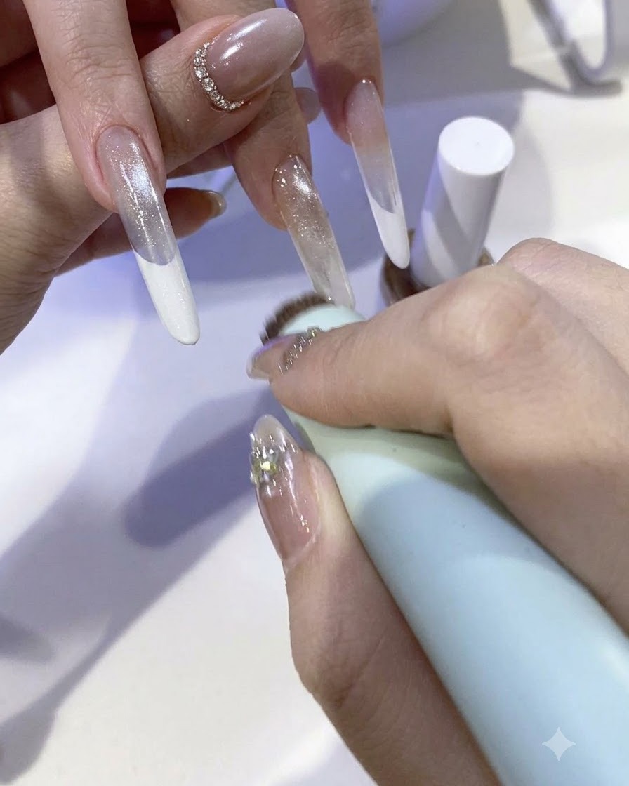 A brush applying a sparkling fairy powder gel mixture onto the tip of an extended nail.