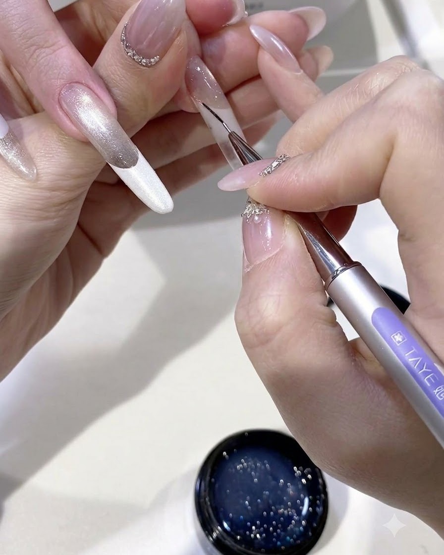 A fine liner brush drawing detailed tassel lines with uncured gel onto the nail surface.