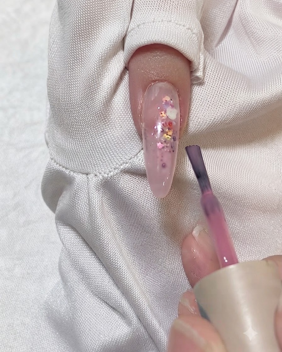 A nail being wiped clean with a lint-free wipe and cleanser.