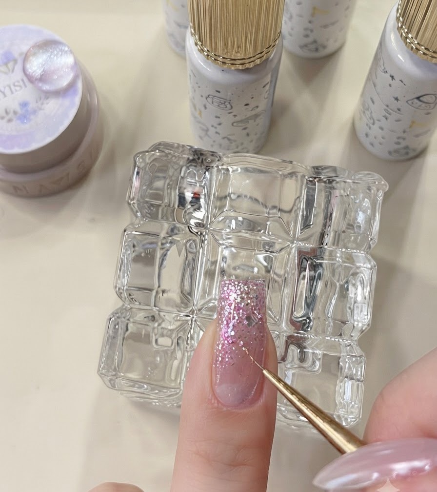A detail tool placing star flakes onto an uncured glitter nail.