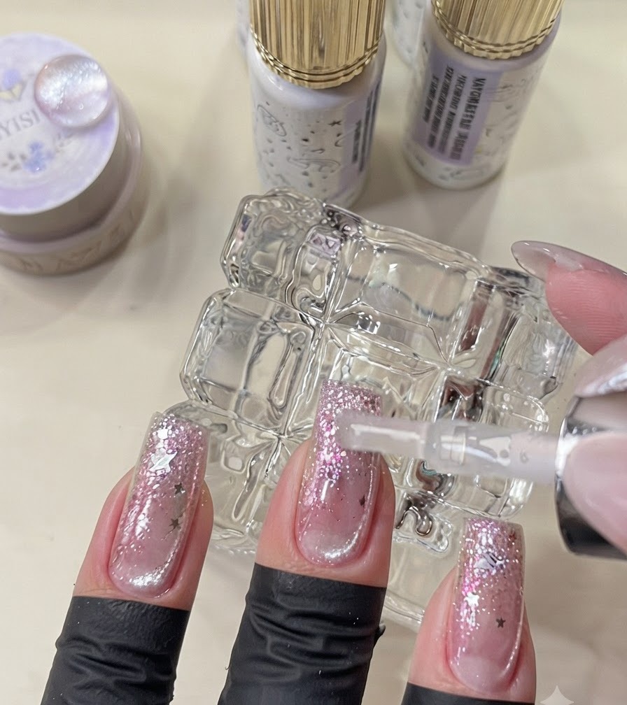 A brush applying final top coat on completed galaxy style nails.