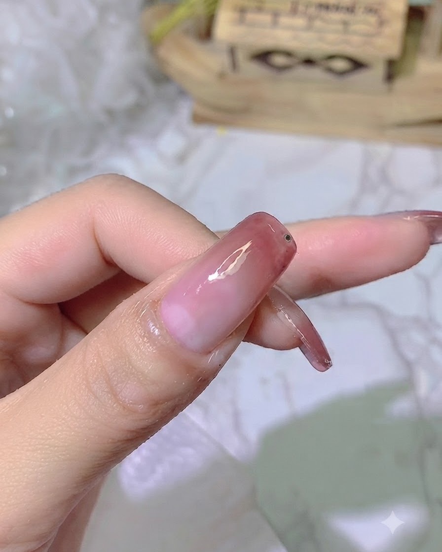 A tiny drop of clear adhesive gel placed near the edge of the finished gradient nail.