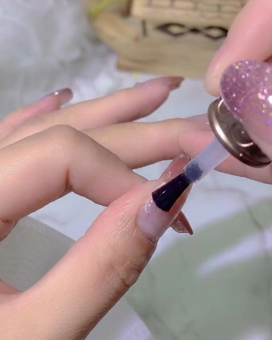 A hand placed under a UV/LED nail lamp curing the top coat layer.