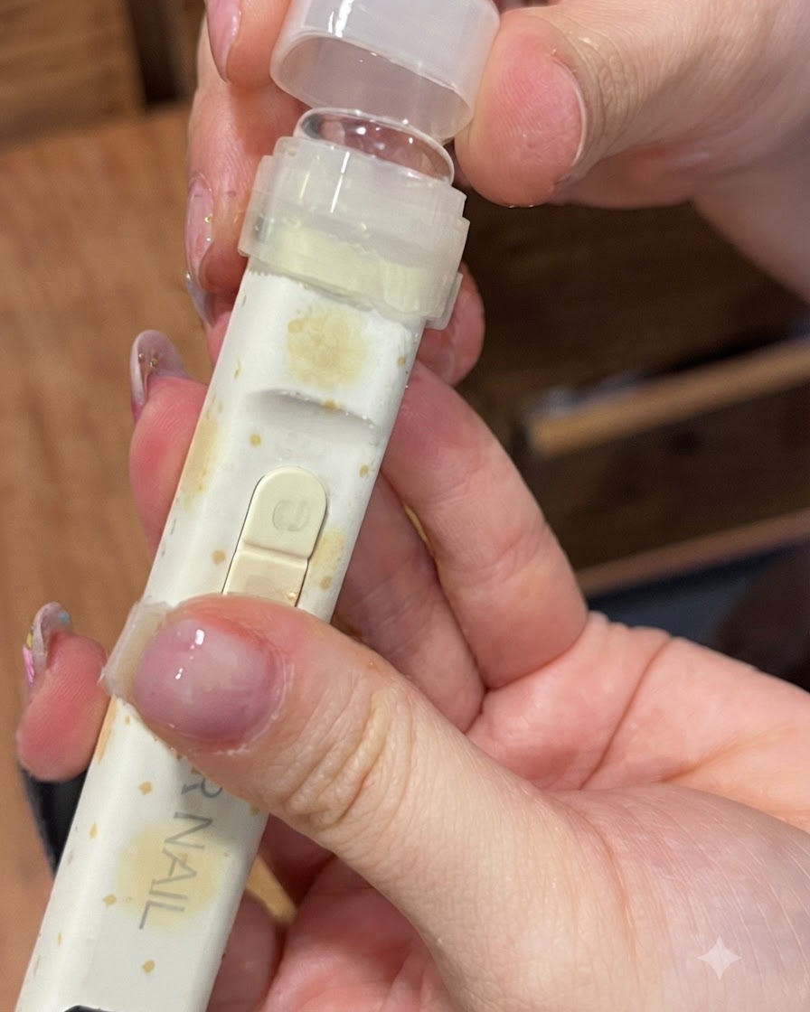 A portable UV/LED nail lamp fitted with a clear silicone pressing tip being held over a finger.