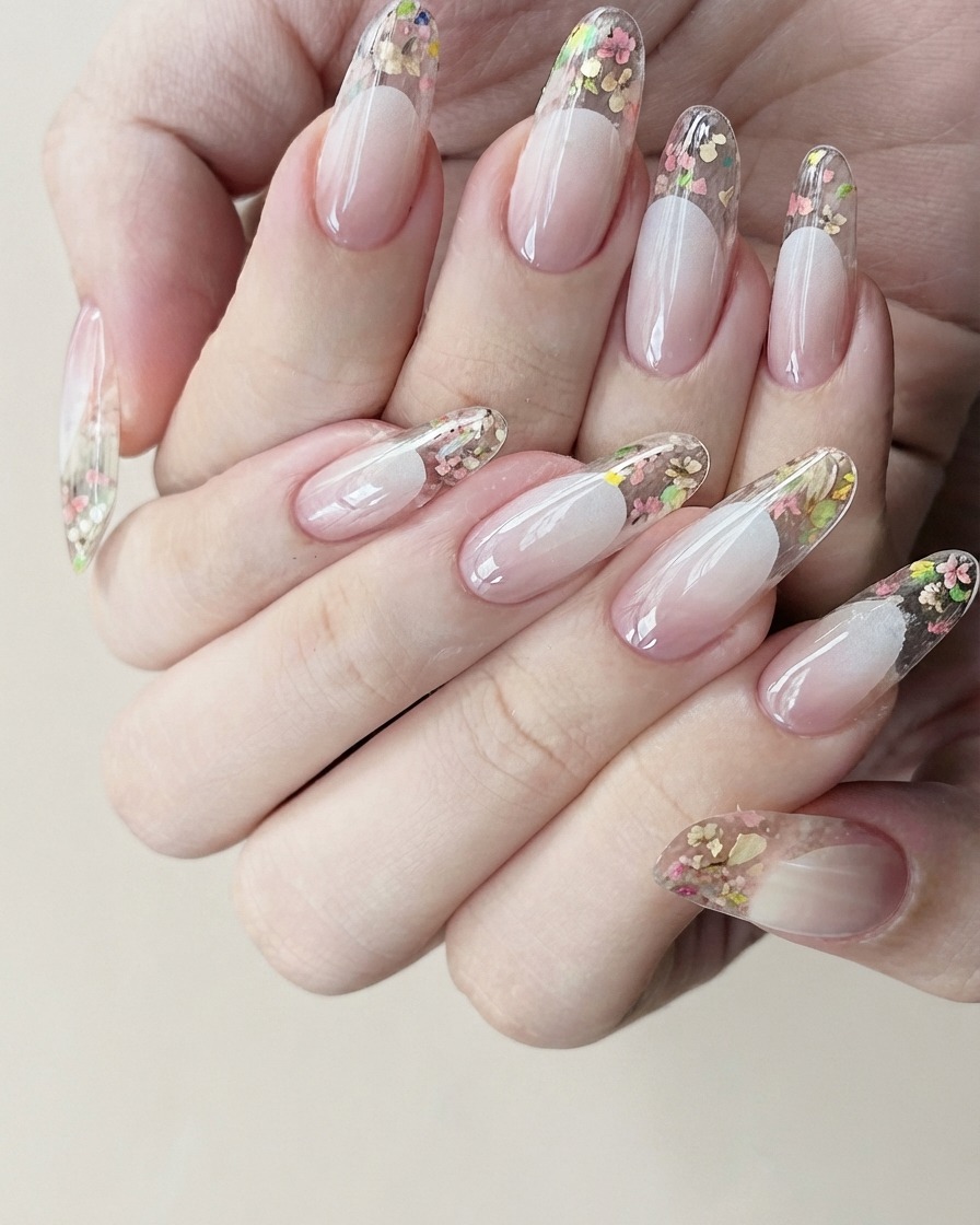A close-up view of a hand carefully peeling off a white French manicure guideline sticker from a clear gel nail.