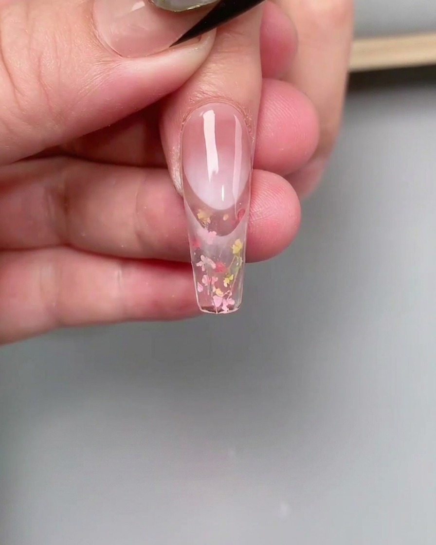 A fine liner brush blending pink gel polish at the cuticle area of a nail to create a gradient effect.
