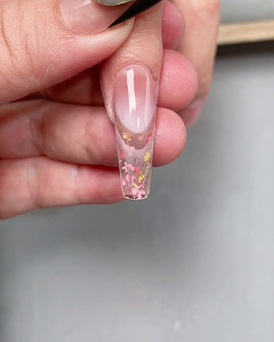 A detail view of base gel being applied to the front portion of a decorated nail.