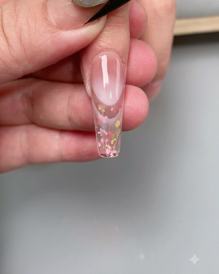 A close-up of a nail curing under the pink glow of a UV/LED nail lamp.