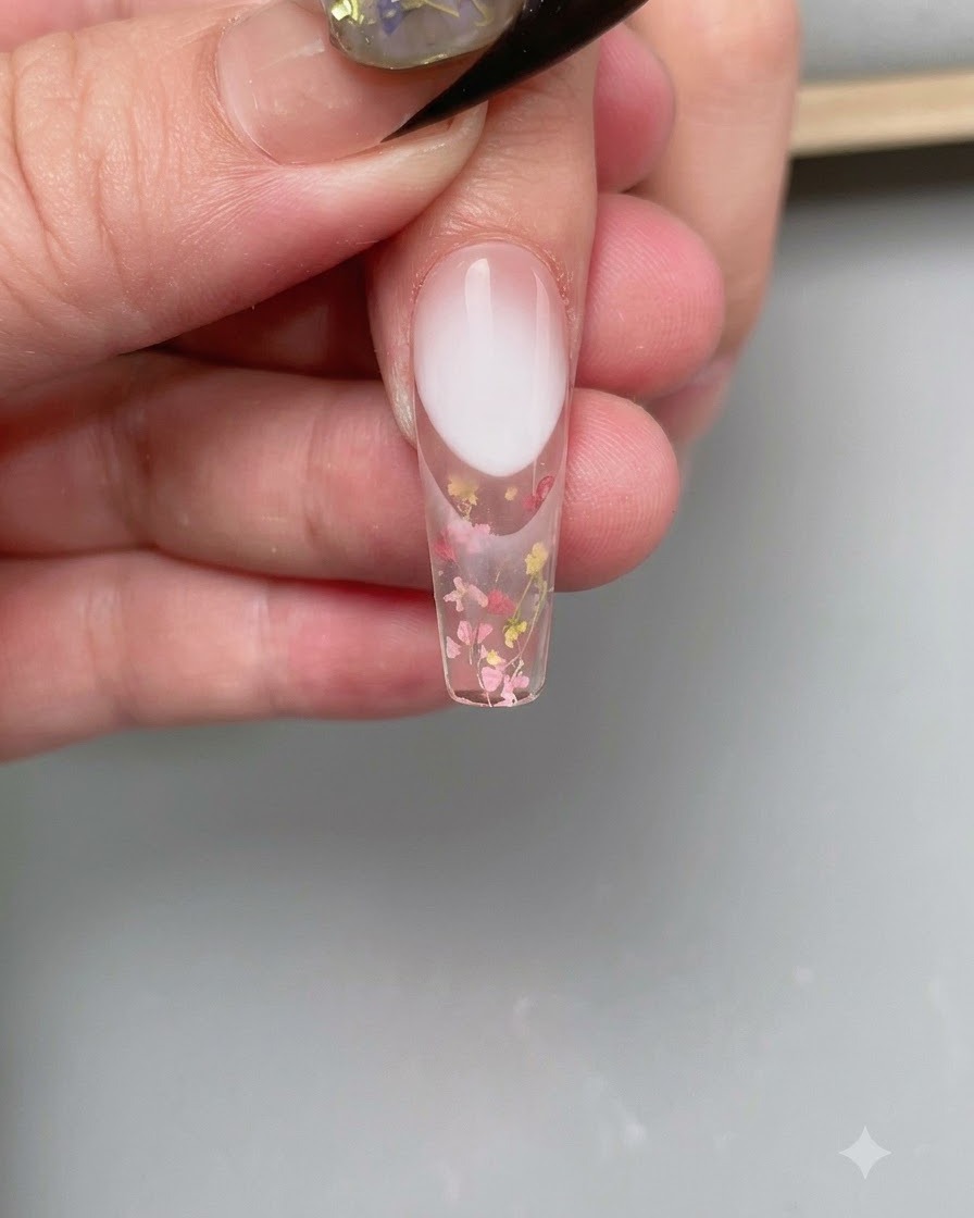 A pair of tweezers placing a curved French nail sticker guide onto the tip of the nail.