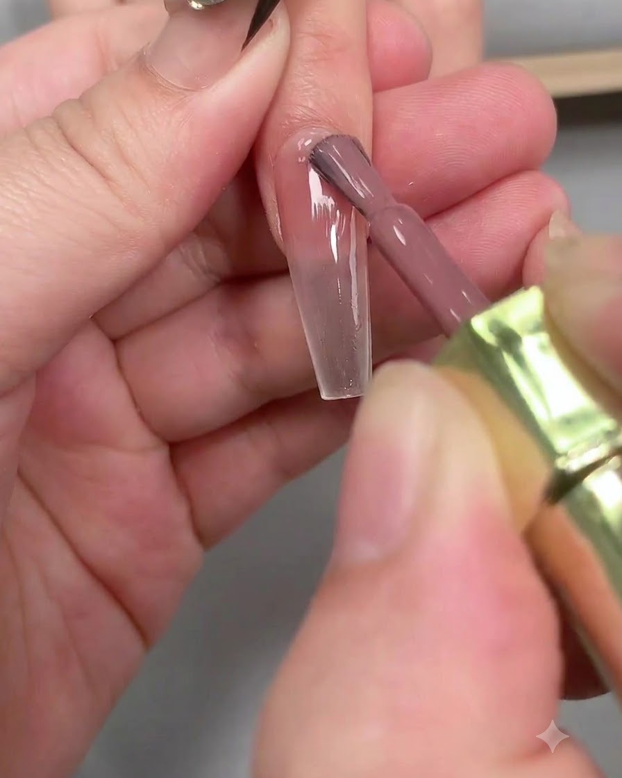 A pair of tweezers carefully peeling off a white French guide sticker from an elongated coffin-shaped nail.