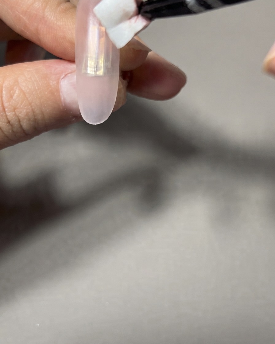 A makeup sponge being used to dab and blend the gradient edges on a nail.