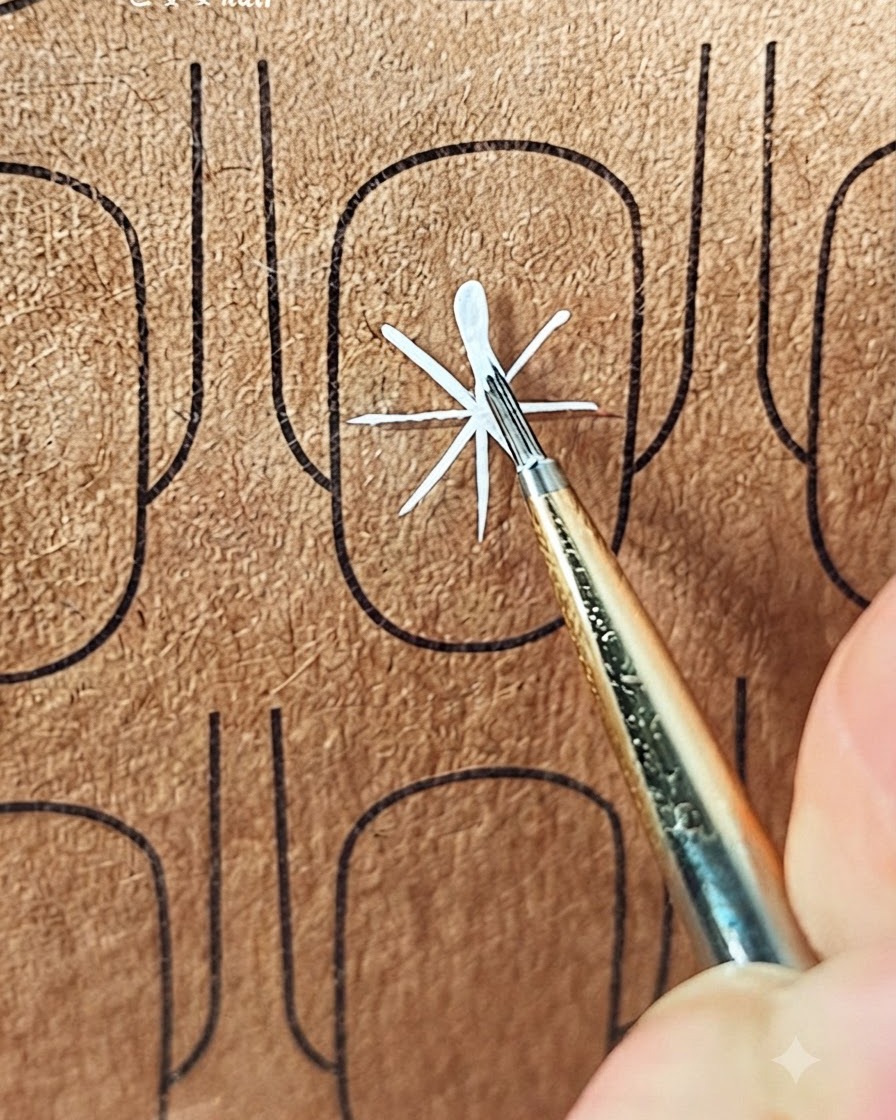 A fine brush creating the first stroke of a white petal outward from the center of the guide lines.
