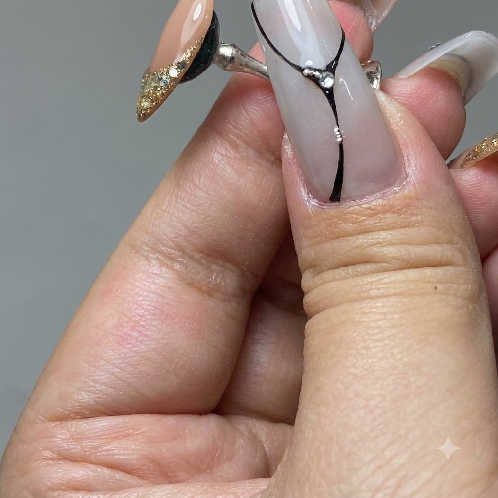 A nail brush spreading gold platinum gel over the tip of a practice nail.