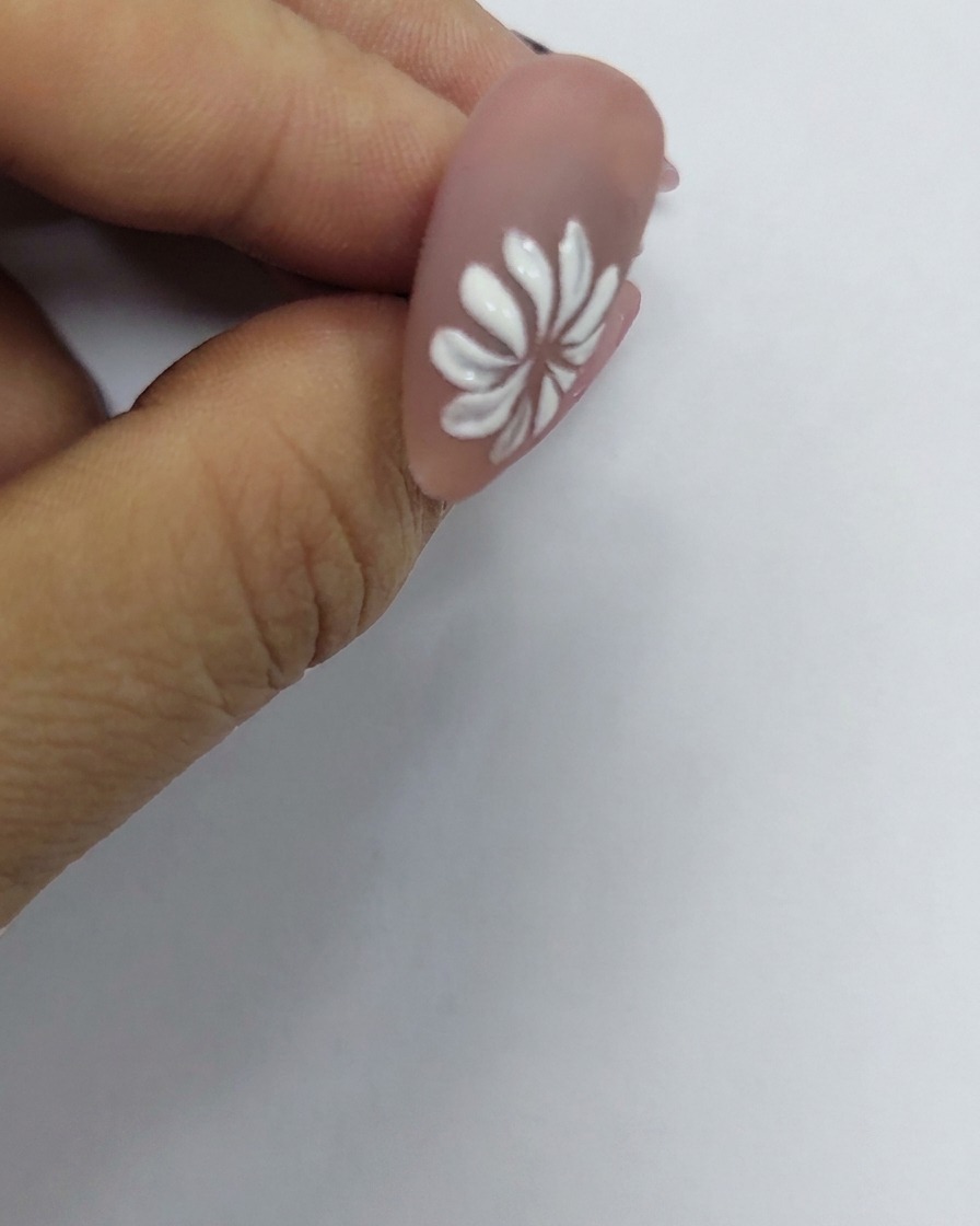 A painted white daisy flower on a nail with a tiny yellow dot placed precisely in its center.