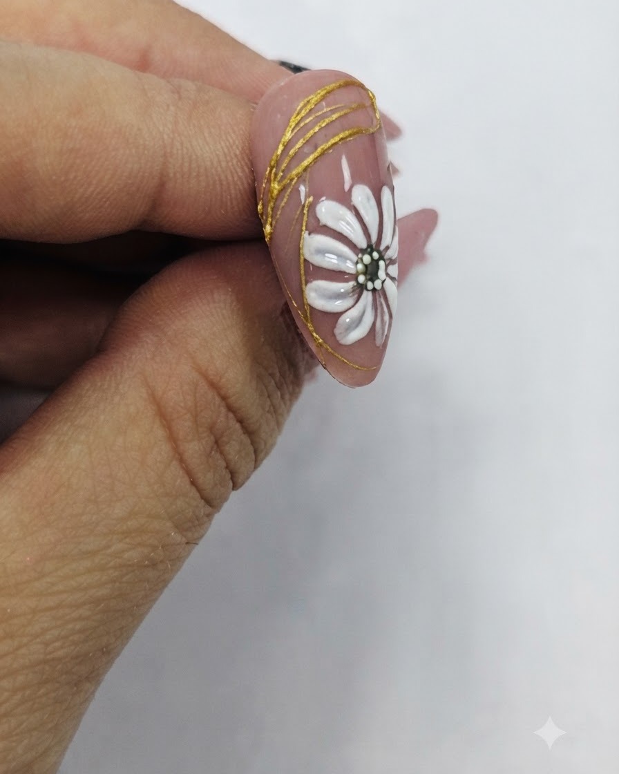 A brush applying a glossy clear top coat over a finished nail design featuring a white daisy and gold accents.